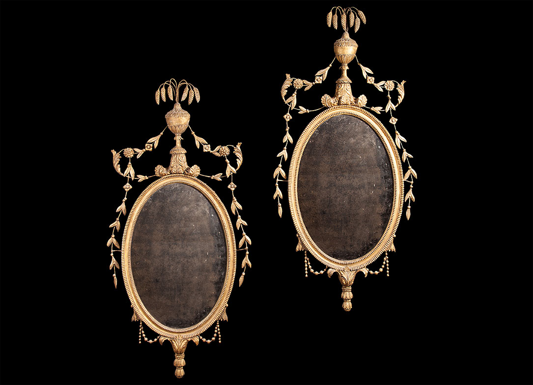 A pair of late 18th century neo-classical ,carved and giltwood oval mirrors with original plates.